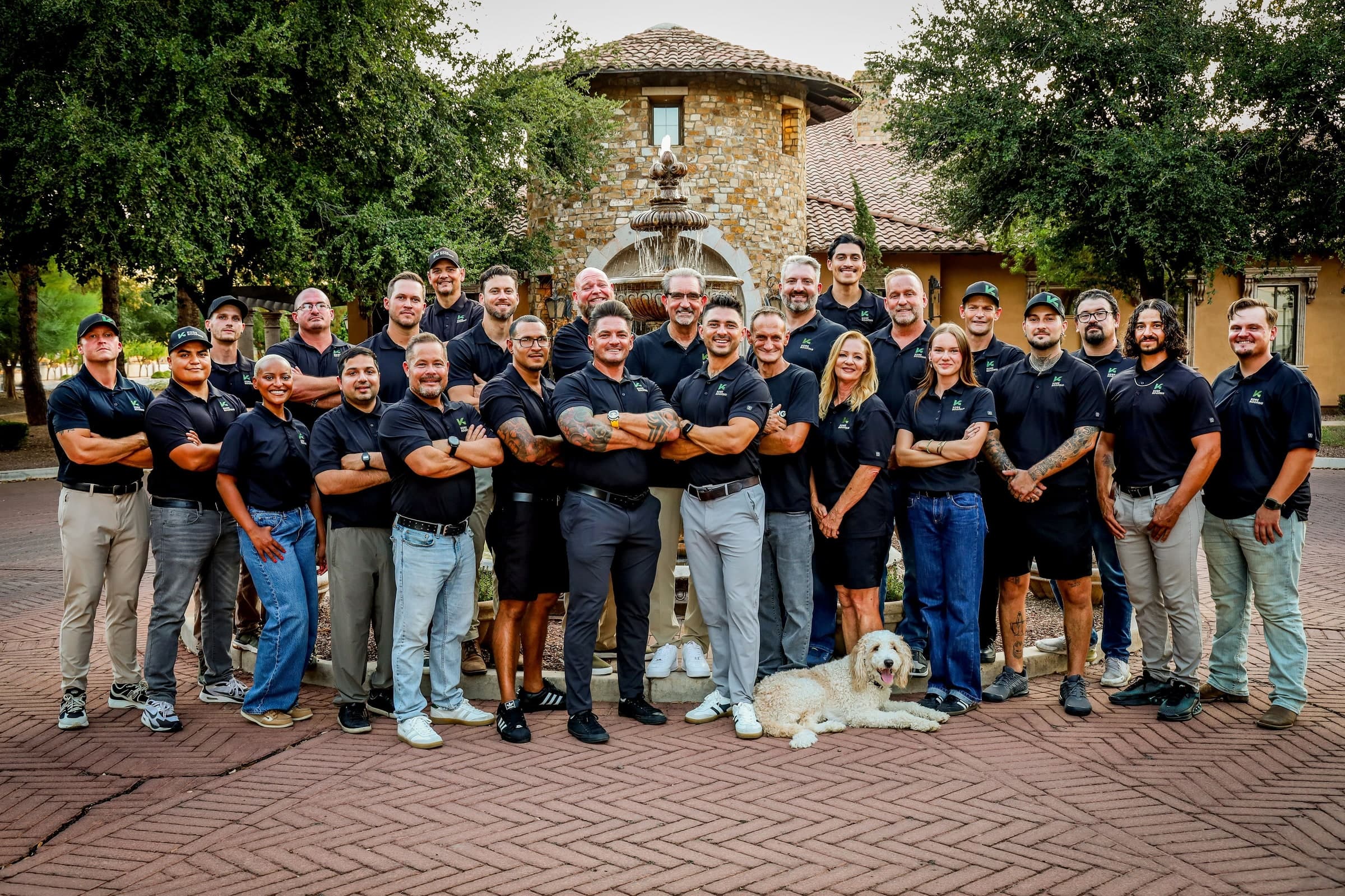 The Kore Roofing team with Molly in front of a courtyard fountain